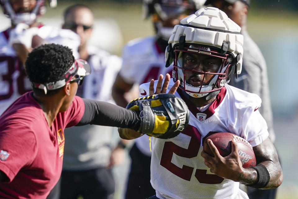 Washington Commanders running back J.D. McKissic, right, runs wearing a Guardian Cap football helmet during practice at the team's NFL football training facility, Wednesday, July 27, 2022 in Ashburn, Va. (AP Photo/Alex Brandon)