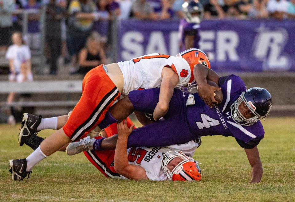 Byron's Maddex Draheim, top, and Jared Claunch sack Rockford Lutheran quarterback Daniel Ballard late in the first quarter of their game at Lutheran on Friday, Sep. 1, 2023.