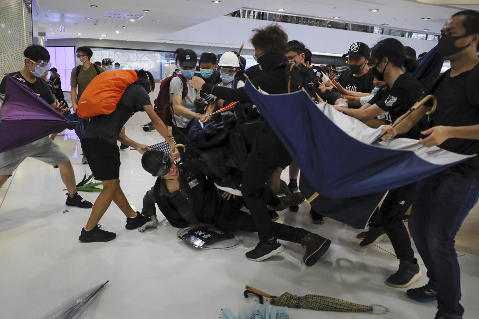 A policeman is attacked by protesters inside a mall in Sha Tin District in Hong Kong, Sunday, July 14, 2019. Police in Hong Kong have fought with protesters as they broke up a demonstration by thousands of people demanding the resignation of the Chinese territory's chief executive and an investigation into complains of police violence. (AP Photo/Kin Cheung)