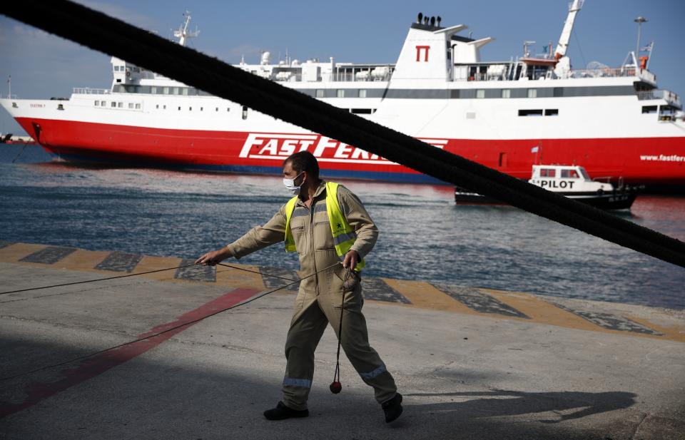 A seaman wearing a face mask to protect against the spread of coronavirus, works outside a ferry at the port of Piraeus, near Athens, Thursday, Aug. 20, 2020. Authorities in Greece are using free on-the-spot tests for ferry passengers and nightlife curfews on popular islands to stem a resurgence of the coronavirus after the country managed to dodge the worst of the pandemic. The number of confirmed virus cases and deaths in Greece remains lower than in many other European countries. (AP Photo/Thanassis Stavrakis)