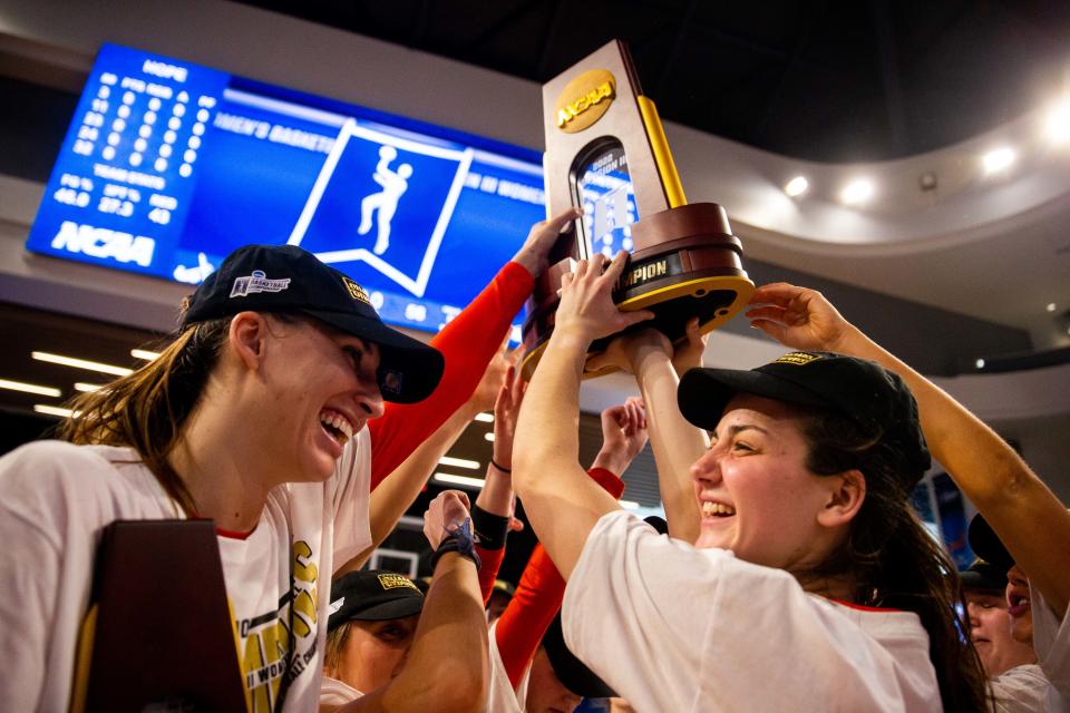 The Hope women's basketball team lift the national championship trophy into the air after their win over UW Whitewater Saturday, March 19, 2022, at UPMC Cooper Fieldhouse in Pittsburgh. 