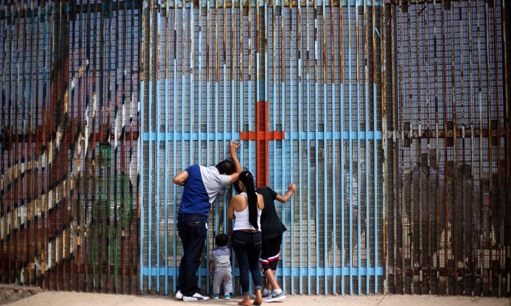 A family talks with relatives through the US-Mexico border fence in Tijuana, Mexico. The Trump administration has unveiled sweeping measures to deport millions of undocumented people. 