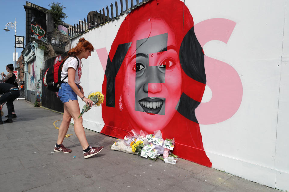 A woman lays flowers next to a mural showing Savita Halappanavar in Dublin, as Ireland goes to the polls to vote in the referendum on the Eighth Amendment of the Irish Constitution. (Photo: Niall Carson/PA Wire)