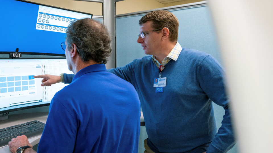 Jason Bloomquist, right, a registered nurse, points to a monitor in St. Luke’s virtual-care center with colleague Grant Haller, also a registered nurse.