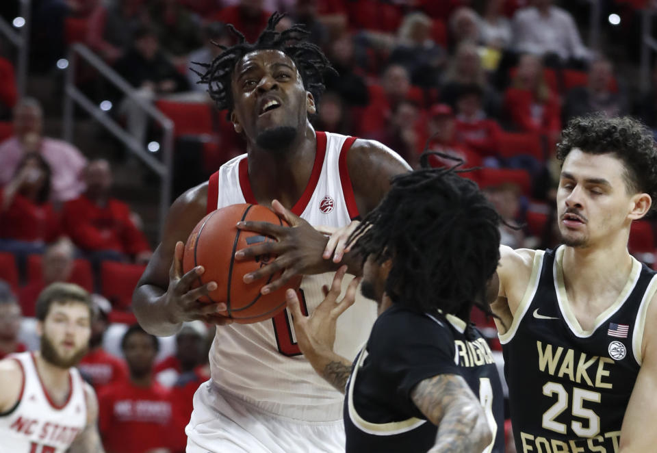 North Carolina State's D.J. Funderburk (0) keeps the ball from Wake Forest's Sharone Wright Jr. (2) and Ismael Massoud (25) during the first half of an NCAA college basketball game in Raleigh, N.C., Friday, March 6, 2020. (Ethan Hyman/The News & Observer via AP)