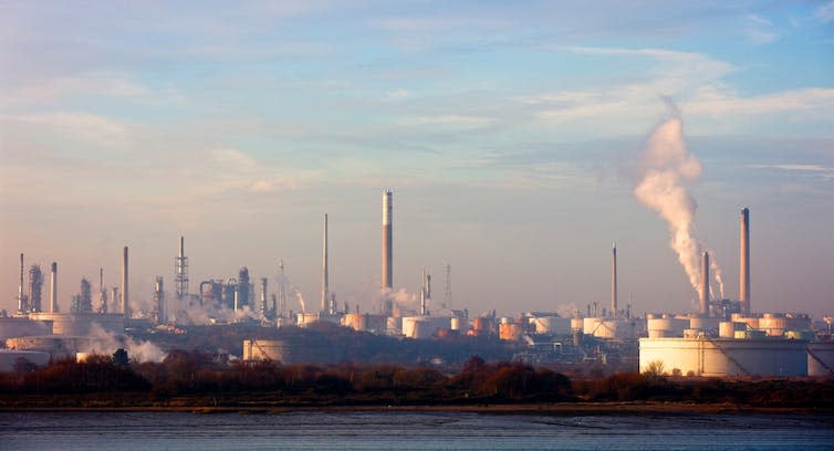 An industrial scene with chimneys and storage tanks.