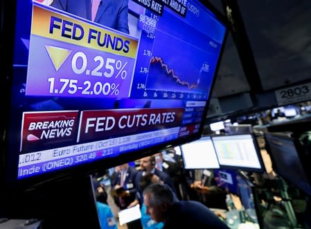 A screen displays the U.S. Federal Reserve interest rates announcement as traders work on the floor of the NYSE in New York