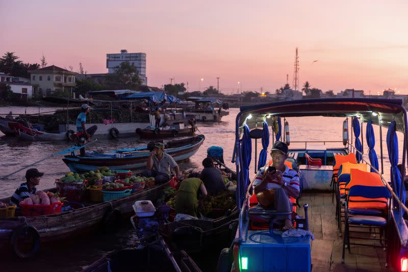 People sit on their boats at Cai Rang floating market on Mekong river, in Can Tho