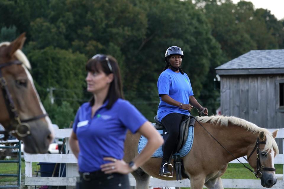 Dionne Williamson, right, of Patuxent River, Md., participates in a riding lesson at Cloverleaf Equine Center in Clifton, Va., Tuesday, Sept. 13, 2022, as Equine Coordinator Clarice Gutman, left, works with another rider. After finishing a tour in Afghanistan in 2013, Williamson, experienced disorientation, depression, memory loss and chronic exhaustion. “It’s like I lost me somewhere,” said the Navy lieutenant commander. After fighting for years to get the help she needed, she eventually found stability through a monthlong hospitalization and a therapeutic program that incorporates horseback riding. (AP Photo/Susan Walsh)