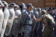 FILE- In this file photo taken on Wednesday, April 18, 2018, Opposition leader Nikol Pashinian, right, speaks to a police officer in front of a police line blocking the way to demonstrators protesting the former president's shift into the prime minister's seat in Yerevan, Armenia. Armenians are set to cast ballots in parliamentary elections expected to cement the incumbent prime minister's grip on power. (Narek Aleksanyan, PAN Photo via AP, File)