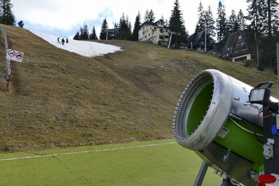 People walk on a patch of melting artificial snow in Vlasic, a ski resort affected by unusual warm weather in Bosnia, Tuesday, Jan. 3, 2023. The exceptional wintertime warmth is affecting ski resorts across Bosnia, prompting tourism authorities in parts of the country to consider declaring a state of natural emergency. (AP Photo/Almir Alic)