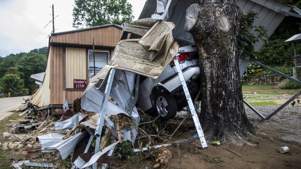 The wreckage of a mobile home and a car are smashed into a tree on the East Fork Pigeon River in Cruso, North Carolina, on August 20, 2021, following Tropical Storm Fred. – Travis Long/AP