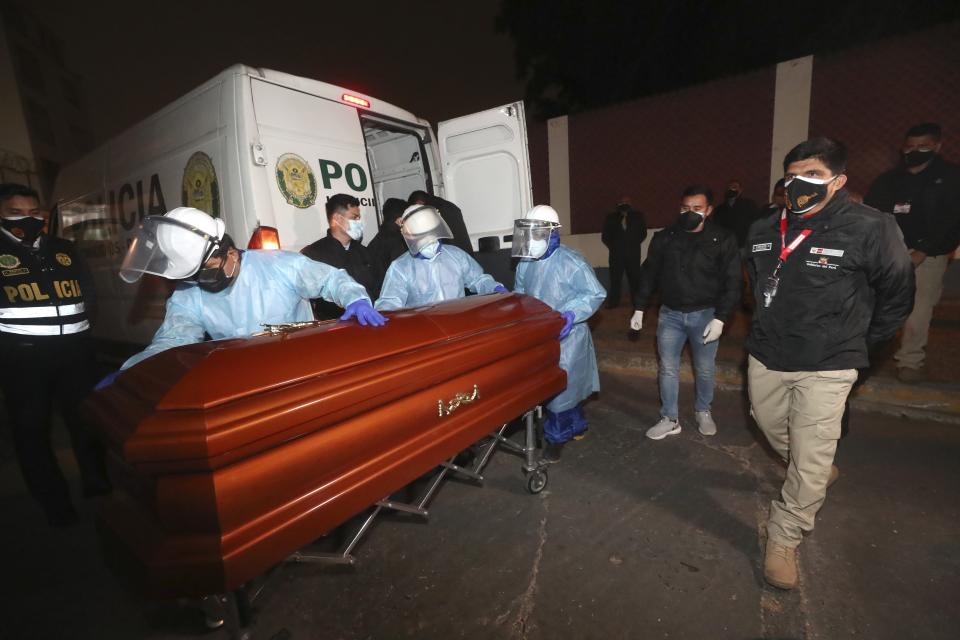 In this photo provided by Peru's Interior Ministry, health workers push the coffin of Abimael Guzman, founder and leader of the Shining Path guerrilla movement, at a crematorium in Callao, Peru, Friday, Sept. 24, 2021. The Peruvian government cremated Guzman on Friday, according authorities. (Rolly Reyna/Peruvian Interior Ministry via AP)