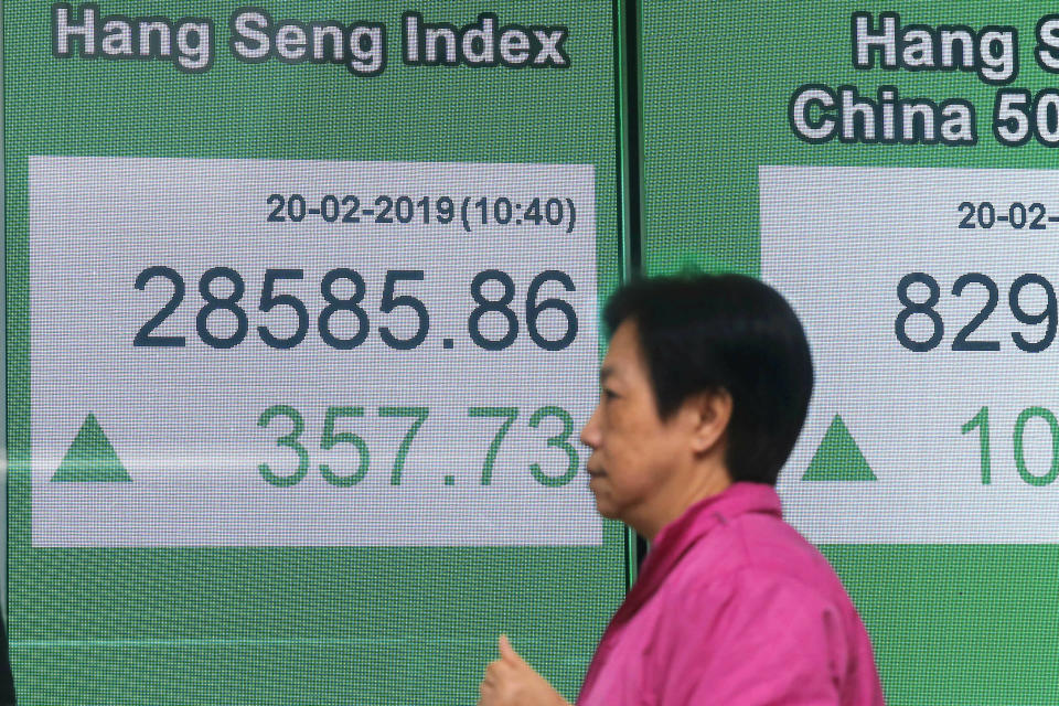 A woman walks past an electronic board showing Hong Kong share index outside a bank in Hong Kong, Wednesday, Feb. 20, 2019. Shares were mostly higher in Asia on Wednesday after a modestly high finish on Wall Street that extended the market’s gains into a fourth week.(AP Photo/Kin Cheung)