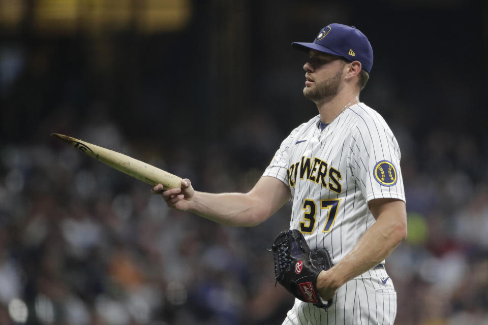 Milwaukee Brewers' Adrian Houser picks up part of a broken bat during the fifth inning of the team's baseball game against the Chicago White Sox on Friday, July 23, 2021, in Milwaukee. (AP Photo/Aaron Gash)