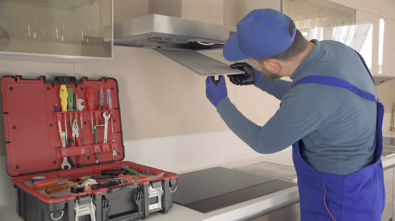 Person performing maintenance on range hood