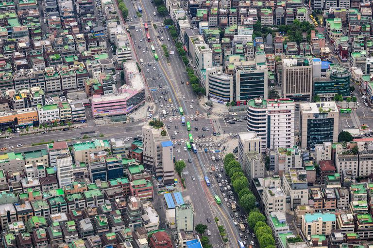Una vista general muestra vehículos circulando por las avenidas principales bordeadas de edificios residenciales y comerciales en el distrito de Gangnam, Seúl.
