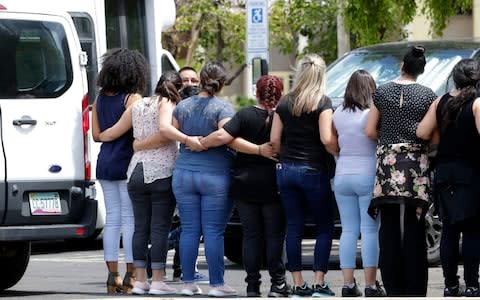 Lutheran Social Services workers link arms to obscure children arriving with adults in Phoenix to be reunited - Credit: Matt York/AP