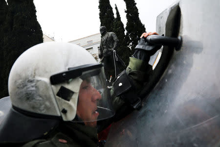 A riot police officer clashes with Greek Communist Party supporters who tried to bring down a statue of former U.S. President Harry Truman, seen in the background, during a demonstration against air strikes on Syria by the United States, Britain and France, in Athens, Greece April 16, 2018. REUTERS/Alkis Konstantinidis