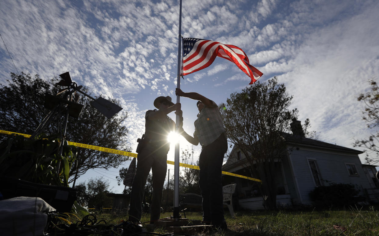 A law enforcement officer helps a man change a flag to half-staff near the scene of a shooting at the First Baptist Church of Sutherland Springs to honor victims, Nov. 6, 2017, in Sutherland Springs, Texas. (Photo: Eric Gay/AP)