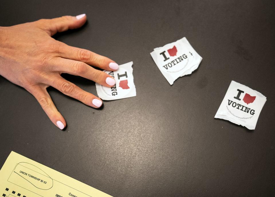 Kelli Biehle grabs an Ohio  "I Love (Heart) Voting" sticker after casting her ballot Tuesday at the Union Township Hall in Hebron.