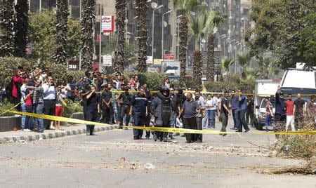 A bomb detonation expert walks in his suit next security personnel before defusing a bomb found in an area in Giza, south of Cairo August 14, 2014. REUTERS/Mohamed Abd El Ghany