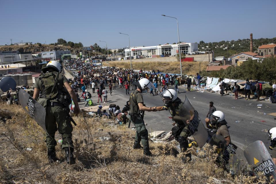 Migrants take part in a rally as riot police block the road near Mytilene town, on the northeastern island of Lesbos, Greece, Friday, Sept. 11, 2020. Thousands of protesting refugees and migrants left homeless on the Greek island of Lesbos after fires destroyed the notoriously overcrowded Moria camp have gathered on a road leading to the island's main town, demanding to be allowed to leave. (AP Photo/Petros Giannakouris)