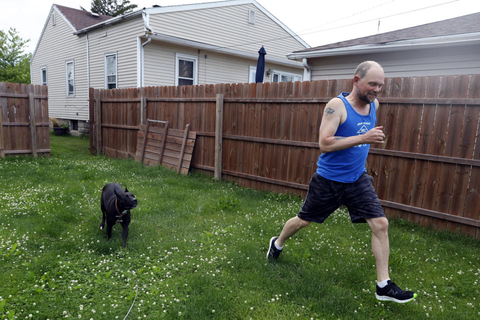 Christian Hainds plays with his dog, Reyna in the backyard of his home in Hammond, Ind., Monday, June 7, 2021. Health officials have warned since early on in the pandemic that obesity and related conditions such as diabetes were risk factors for severe COVID-19. It wasn't until he was diagnosed as diabetic around the start of the pandemic that he felt the urgency to make changes. Hainds lost about 50 pounds during the pandemic, and at 180 pounds and 5 feet, 11 inches tall is no longer considered obese. (AP Photo/Shafkat Anowar)