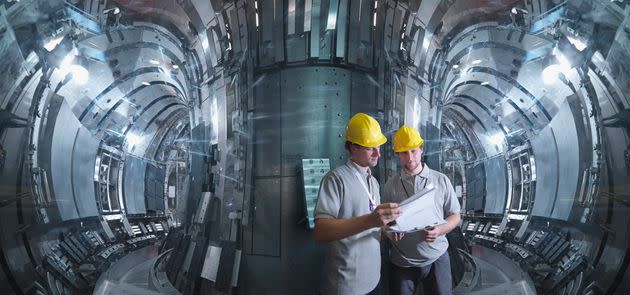 Dos científicos trabajan en un reactor de fusión nuclear.