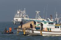 In this Tuesday, April 22, 2014, searchers and divers look for people believed to have been trapped in the sunken ferry Sewol near buoys which were installed to mark the vessel in the water off the southern coast near Jindo, south of Seoul, South Korea. One by one, coast guard officers carried the newly arrived bodies covered in white sheets from a boat to a tent on the dock of this island, the first step in identifying a sharply rising number of corpses from the South Korean ferry that sank nearly a week ago. (AP Photo/Korea Pool) KOREA OUT