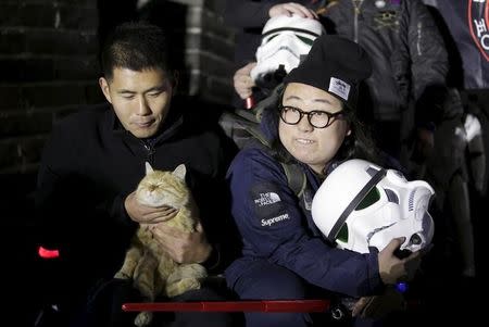 A fan holding a helmet of the Stormtrooper character from "Star Wars" poses for a group photo next to a cat at the Juyongguan section of the Great Wall of China during a promotional event for "Star Wars: The Force Awakens" film, on the outskirts of Beijing, China, October 20, 2015. REUTERS/Jason Lee