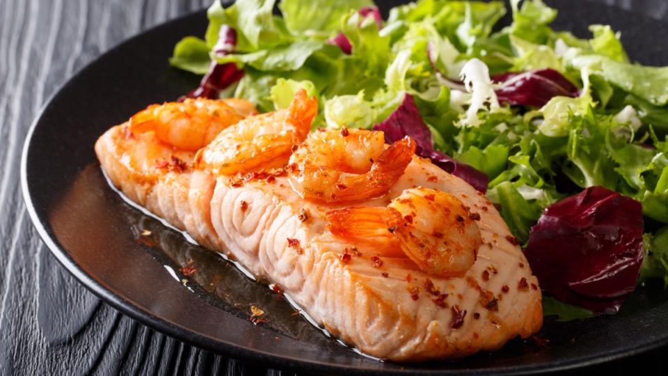 A plate of salmon and shrimp with a salad