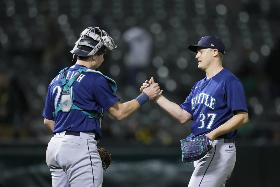 Seattle Mariners pitcher Paul Sewald, right, and catcher Cal Raleigh celebrate after the team's 2-1 victory over the Oakland Athletics in a baseball game in Oakland, Calif., Tuesday, May 2, 2023. (AP Photo/Godofredo A. Vásquez)