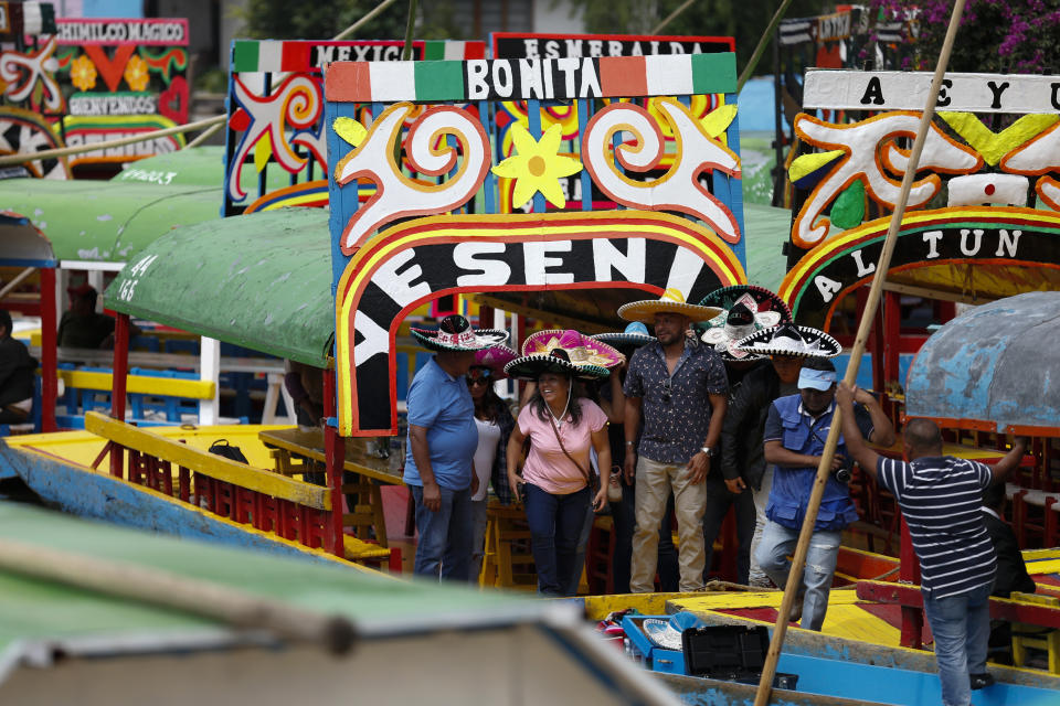 A group of visitors wearing sombreros disembarks from a trajinera, the colorful boats typically rented by tourists, families, and groups of young people, in Xochimilco, Mexico City, Friday, Sept. 6, 2019. The usually festive Nativitas pier was subdued and largely empty Friday afternoon, with some boat operators and vendors estimating that business was down by 80% on the first weekend following the drowning death of a youth that was captured on cellphone video and seen widely in Mexico. Borough officials stood on the pier to inform visitors of new regulations that went into effect Friday limiting the consumption of alcohol, prohibiting the use of speakers and instructing visitors to remain seated.(AP Photo/Rebecca Blackwell)