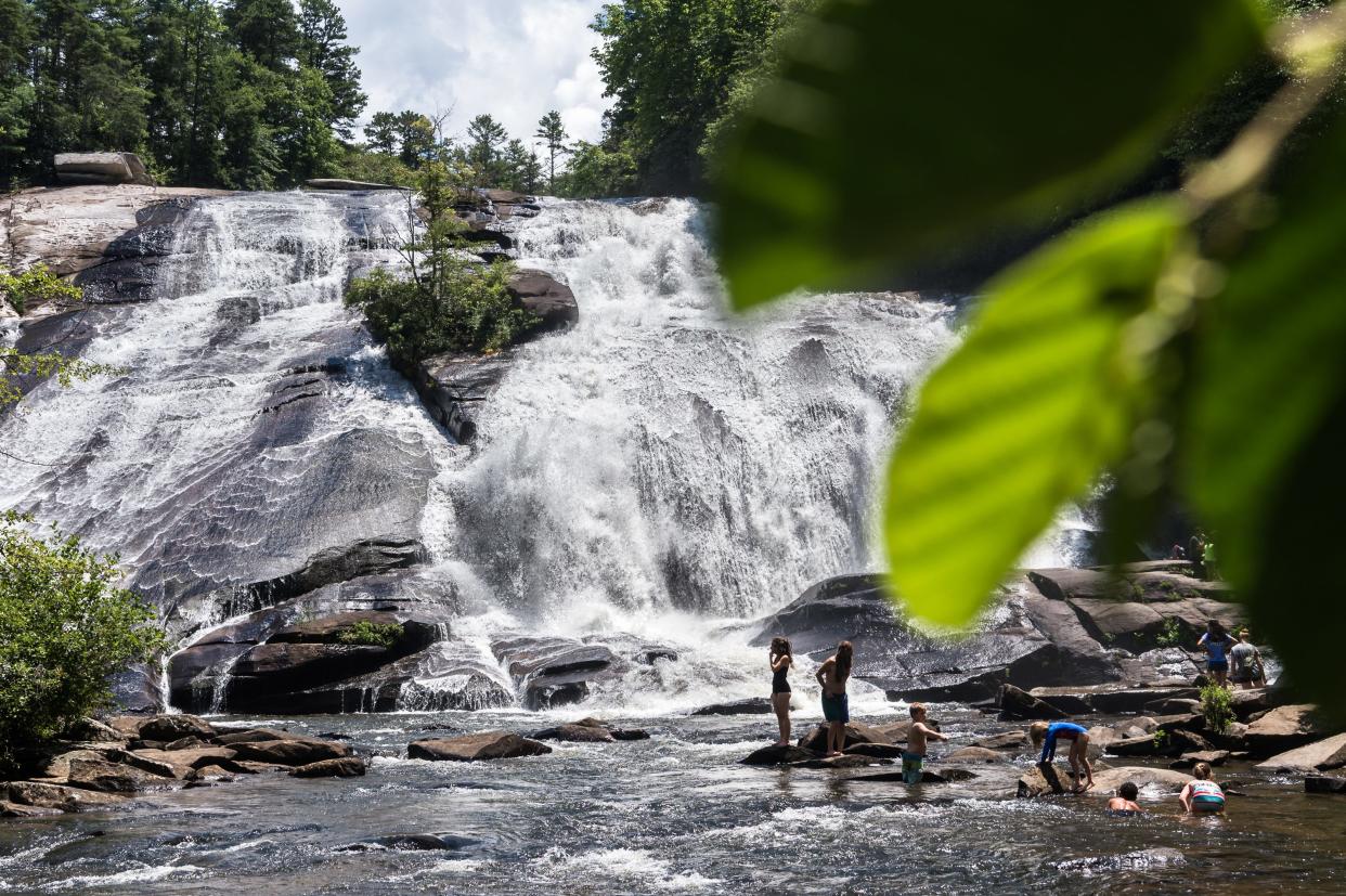 Visitors to DuPont State Recreational Forest wade into the water at the base of High Falls Thursday, July 26, 2018.