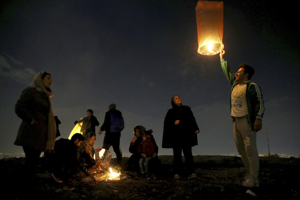 An Iranian man releases a lit lantern during a celebration, known as "Chaharshanbe Souri," or Wednesday Feast, marking the eve of the last Wednesday of the solar Persian year, Tuesday, March 19, 2019 in Tehran, Iran. Iran's many woes briefly went up in smoke on Tuesday as Iranians observed a nearly 4,000-year-old Persian tradition known as the Festival of Fire. (AP Photo/Ebrahim Noroozi)