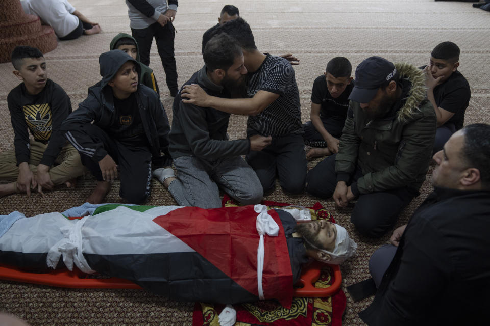 Mourners take the last look at the body of Palestinian Mohammad Shahmawi, 22, at a mosque in the West Bank refugee camp of al-Faraa, Friday, April 12, 2024. Two Palestinians were killed early Friday in confrontations with Israeli forces in the Israeli-occupied West Bank, Palestinian medics and the Israeli military said. The Islamic militant group Hamas said one of those killed was a local commander. (AP Photo/Nasser Nasser)