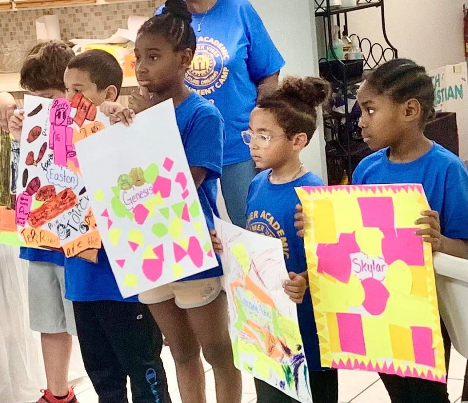 Mack Moselen, Easton Milligan, Genesis Haire, Lazane-Lee Benyard and Skylar Eaddy show off posters they made during the 2023 Summer Academic Enrichment Camp, sponsored and administered by the Harry T. and Harriette V. Moore Cultural Complex board of directors in North Brevard.