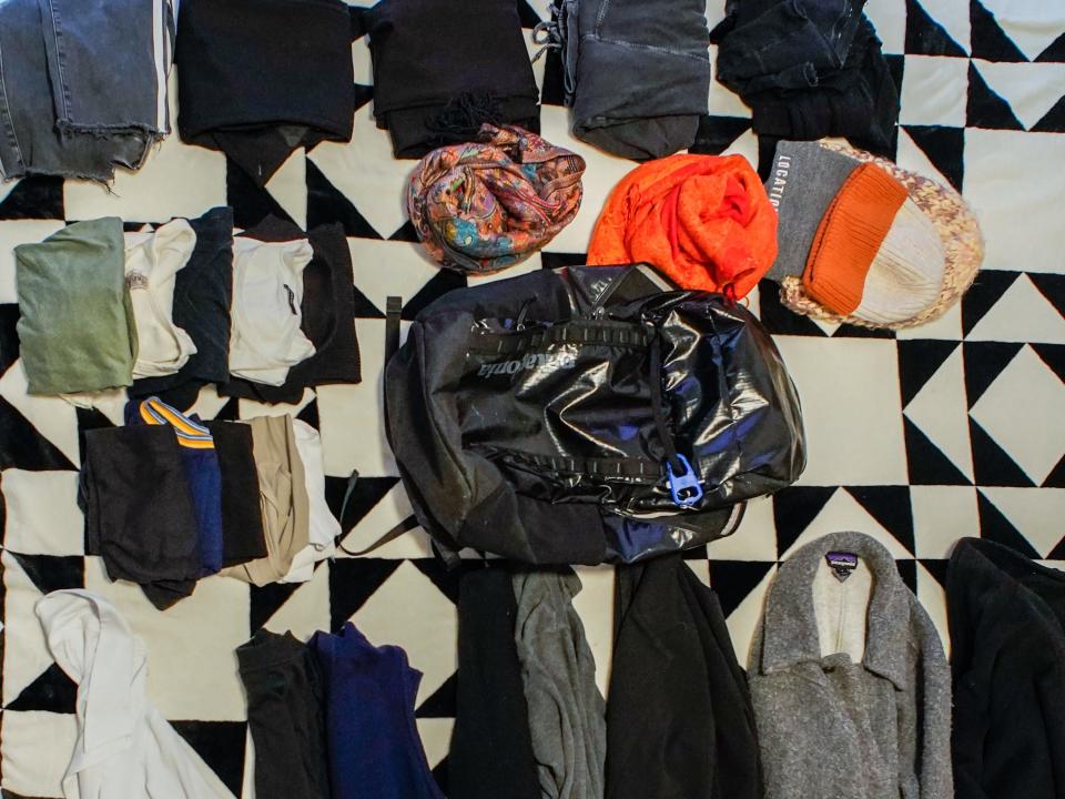 The author's backpack belongings are on a bed with a black-and-white patterned blanket