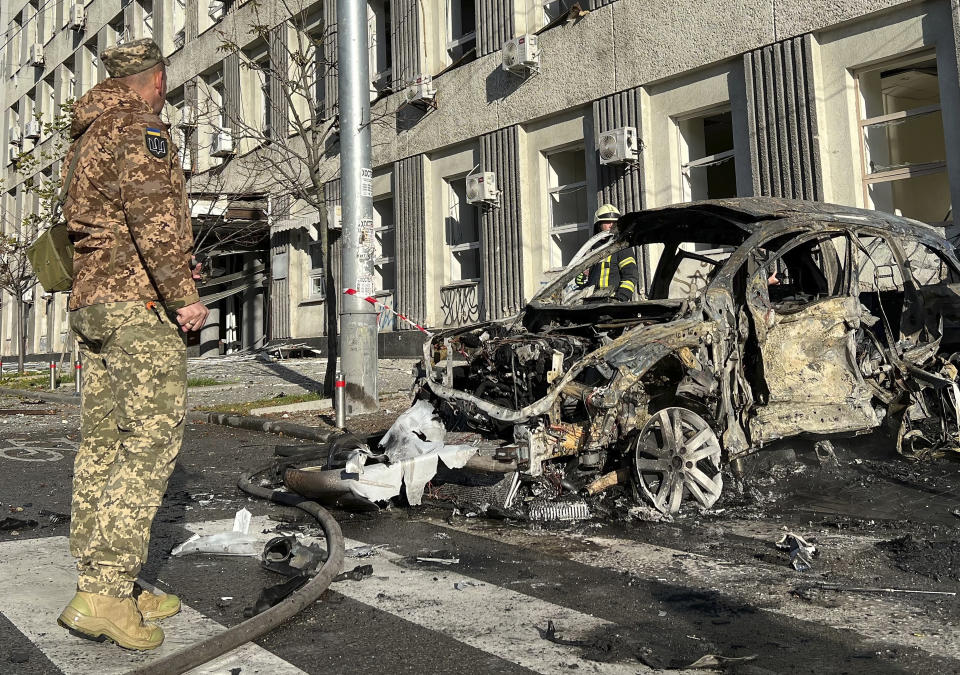 Rescue workers survey the scene of a Russian attack on Kyiv, Ukraine on Monday, Oct. 10, 2022. Two explosions rocked Kyiv early Monday following months of relative calm in the Ukrainian capital. (AP Photo/Adam Schreck)