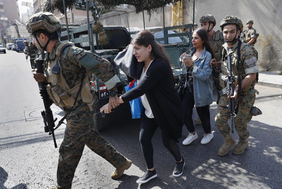 Lebanese army special forces soldiers assist teachers as they flee their school after deadly clashes erupted nearby along a former 1975-90 civil war front-line between Muslim Shiite and Christian areas at Ain el-Remaneh neighborhood, in Beirut, Lebanon, Thursday, Oct. 14, 2021. Armed clashes broke out in Beirut Thursday during the protest against the lead judge investigating last year's massive blast in the city's port, as tensions over the domestic probe boiled over. (AP Photo/Hussein Malla)