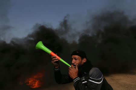 A demonstrator blows a trumpet during a protest where Palestinians demand the right to return to their homeland, at the Israel-Gaza border, in the southern Gaza Strip May 18, 2018. REUTERS/Ibraheem Abu Mustafa