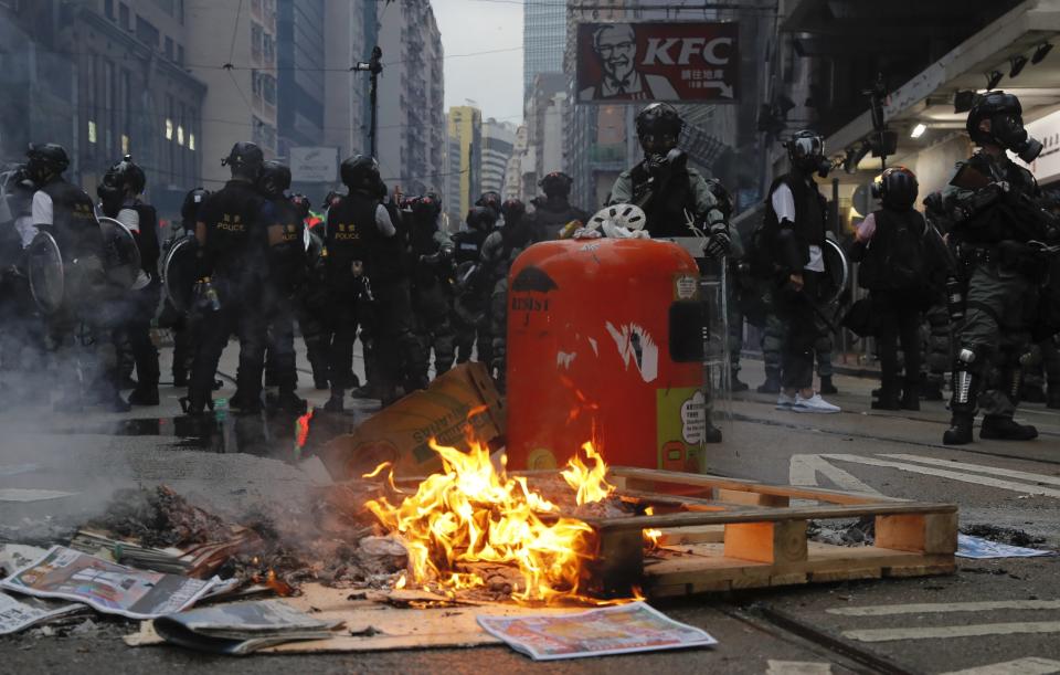 Police stand near fire made by protestors in Hong Kong, Sunday, Oct. 6, 2019. Shouting "Wearing mask is not a crime," tens of thousands of protesters braved the rain Sunday to march in central Hong Kong as a court rejected a second legal attempt to block a mask ban aimed at quashing violence during four months of pro-democracy rallies. (AP Photo/Kin Cheung)