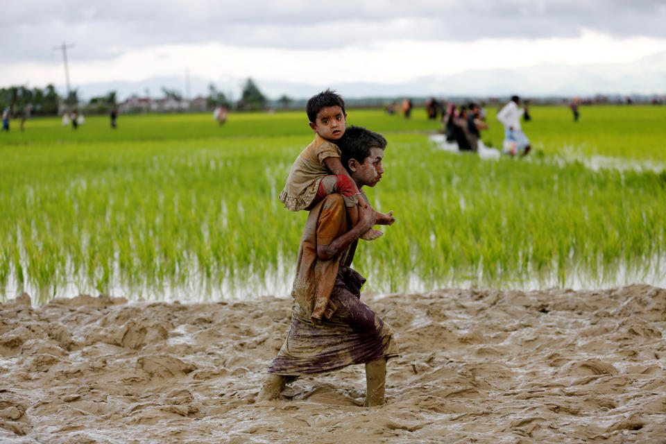 <p>A Rohingya boy carries a child while walking in the mud after crossing the Bangladesh-Myanmar border in Teknaf, Bangladesh, Sept. 1, 2017. (Photo: Mohammad Ponir Hossain/Reuters) </p>