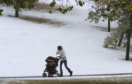 A woman hides her face from the blinding snow during an early year snow fall in Calgary, Alberta September 8, 2014. REUTERS/Todd Korol