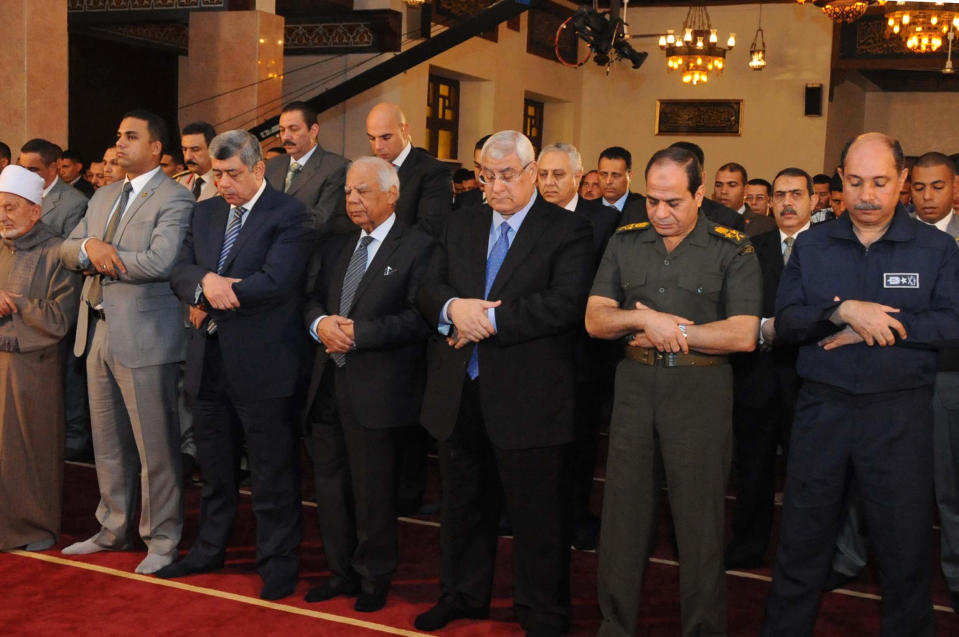 FILE - This Oct. 15, 2013 file photo released by the Egyptian Presidency shows interim President Adly Mansour, center, interim Prime Minister Hazem el-Beblawi, fourth from left, and Defense Minister Gen. Abdel-Fattah el-Sissi, second from right, pray on the first day of Eid al-Aha, or Feast of Sacrifice, in Cairo, Egypt. The head of Egypt’s military, Abdel-Fattah el-Sissi, is riding on a wave of popular fervor that is almost certain to carry him to election as president. Unknown only two years ago, a broad sector of Egyptians now hail him as the nation’s savior after he ousted the Islamists from power, and the state-backed personality cult around him is so eclipsing, it may be difficult to find a candidate to oppose him if he runs. Still, if he becomes president, he faces the tough job of ruling a deeply divided nation that has already turned against two leaders.(AP Photo/Egyptian Presidency, File)