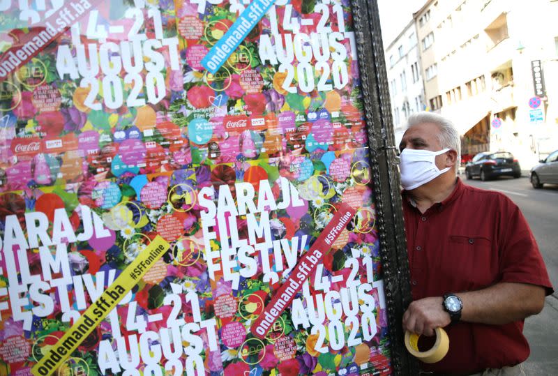 Worker wearing a protective mask sticks a Sarajevo Film Festival poster in Sarajevo