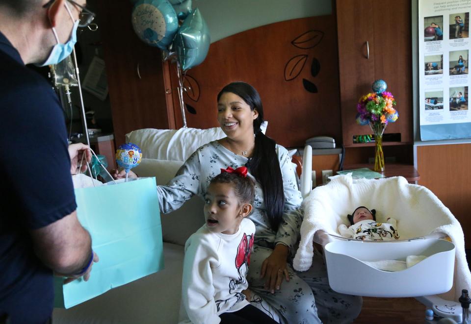 Wentworth-Douglass Hospital security guard Andy Clark brings a gift to Rochela Gonzalez and her family Friday, Sept. 16, 2022. On Monday, Clark helped deliver her son, Tiago in her car.