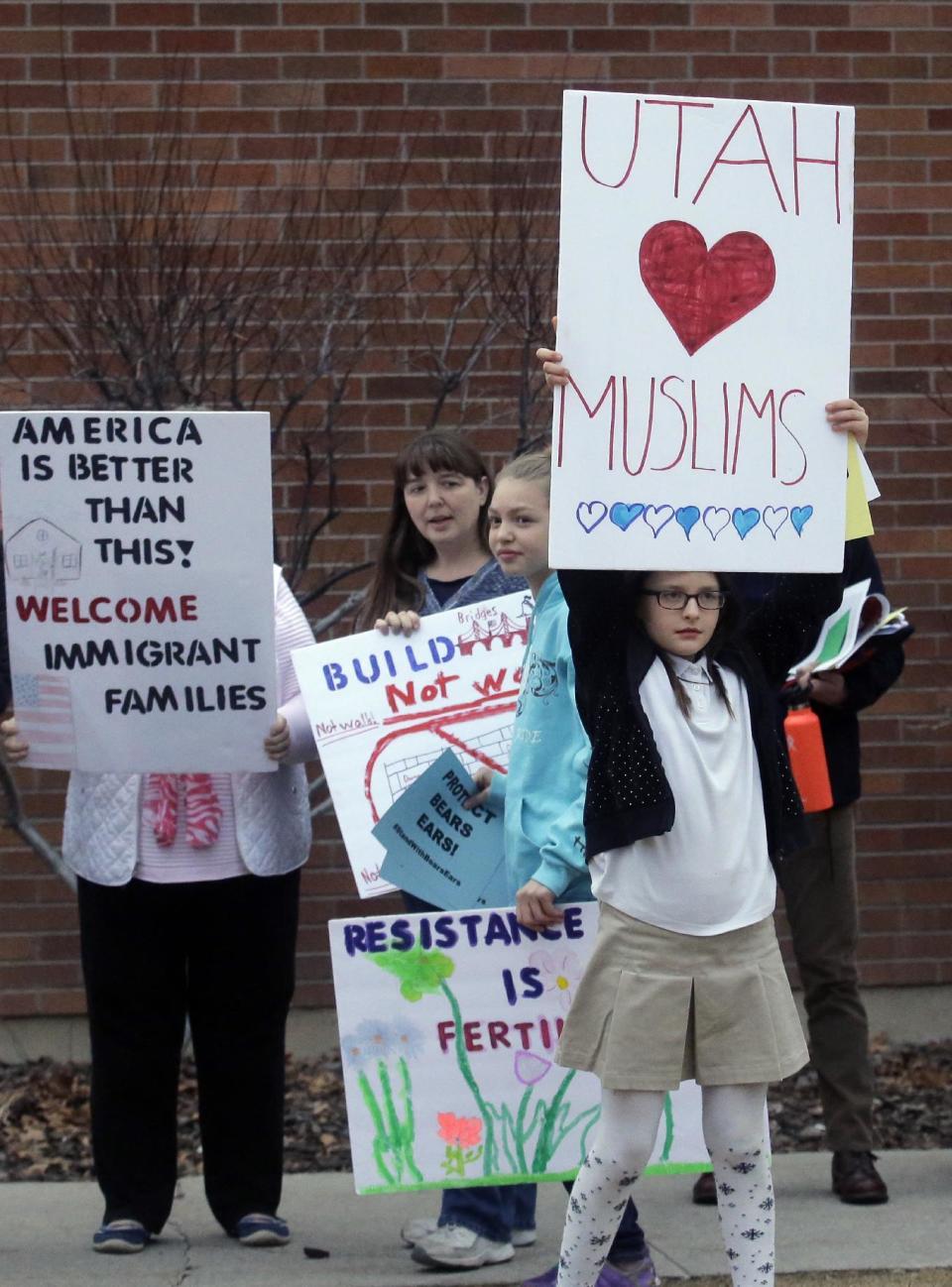 People hold their signs as they gather outside the Brighton High School before U.S. Rep. Jason Chaffetz town hall meeting Thursday, Feb. 9, 2017, in Cottonwood Heights, Utah. His visit came as the congressman spends time in his home state, visiting with Muslim leaders and holding a town hall Thursday night in which he's expected to be greeted by a small band of protesters and face some sharp questions from constituents who are frustrated about his refusal to investigate President Donald Trump's ties to Russia. (AP Photo/Rick Bowmer)