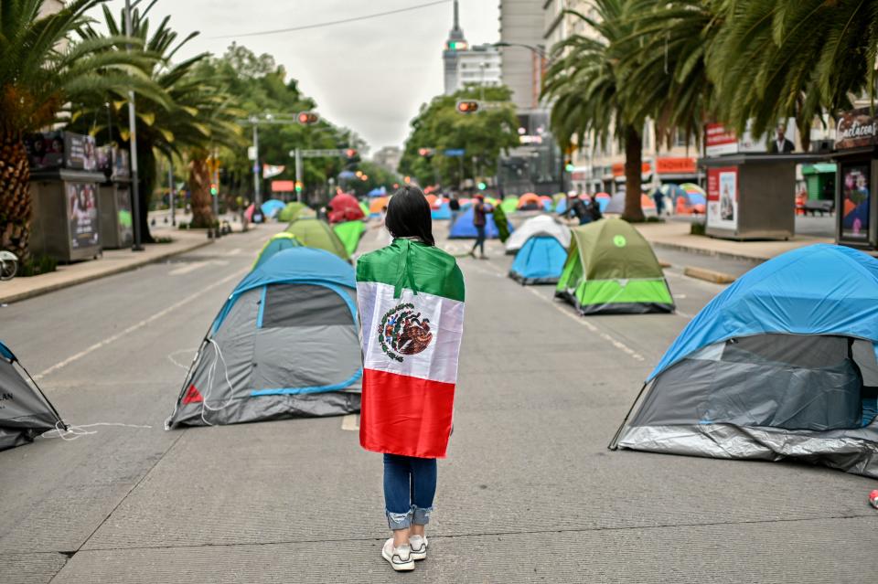 A member of the National Front Anti-AMLO (Frena), which will make a second attempt to reach Zocalo Square to protest against Mexican President Andres Manuel Lopez Obrador (ALMO), remains wrapped in a Mexican flag while camping on Juarez street in Mexico City on September 20, 2020, a day after being prevented by the local police to get to the city's main square, amid the COVID-19 novel coronavirus pandemic. (Photo by PEDRO PARDO / AFP) (Photo by PEDRO PARDO/AFP via Getty Images)